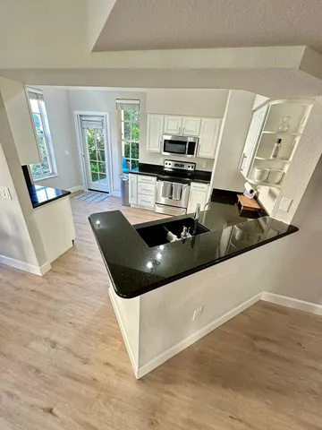 a kitchen with stainless steel appliances kitchen island granite countertop a sink and wooden floors