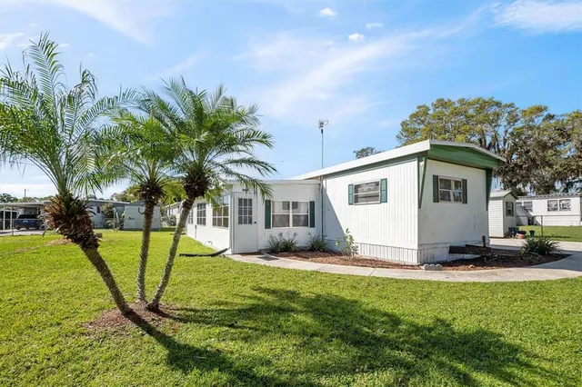 a view of a house with a yard and palm trees