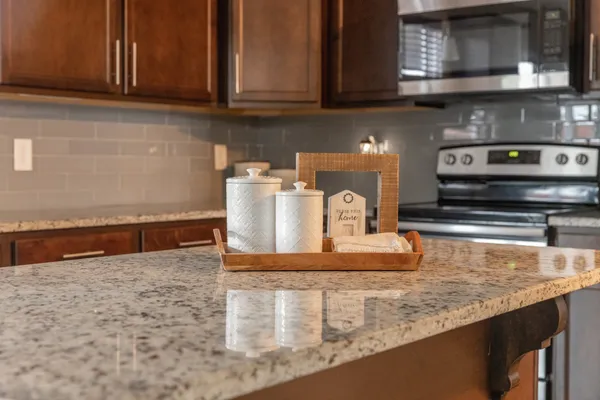 a kitchen with granite countertop a stove a microwave a sink and cabinets
