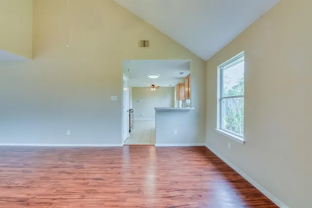 a view of empty room with wooden floor and fan