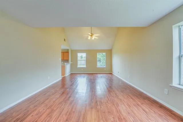 a view of an empty room with wooden floor and a window