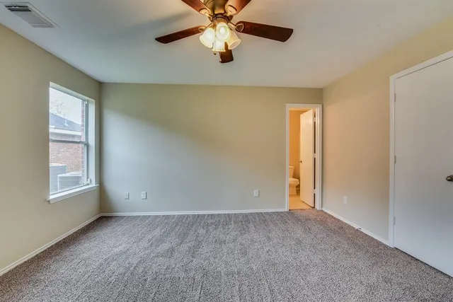 a view of an empty room with window and chandelier fan