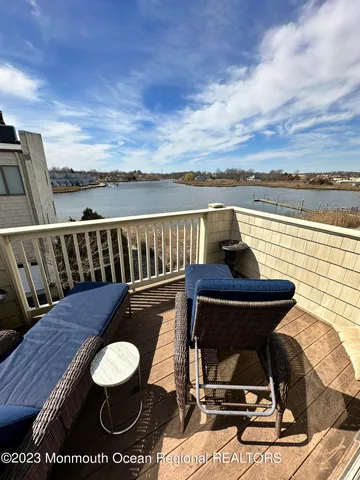 a view of a balcony with wooden floor chairs and a barbeque