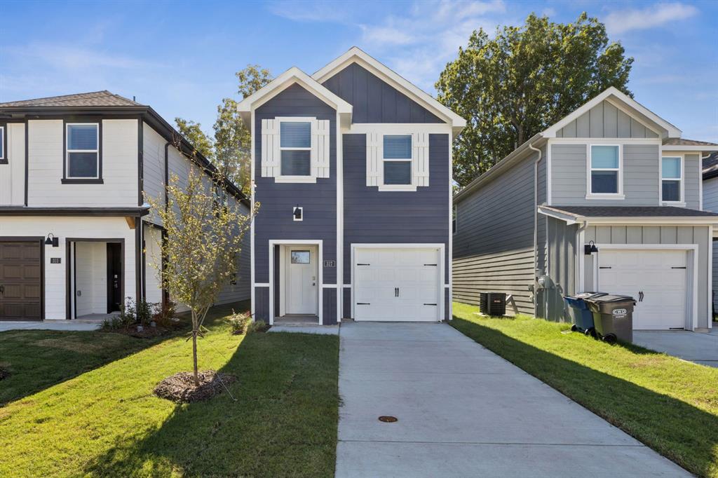 View of front of home with board and batten siding, a garage, and a front lawn