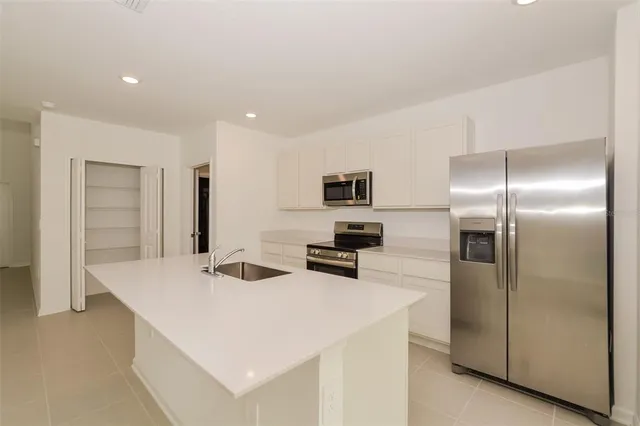 a kitchen that has a refrigerator a stove a microwave and white cabinets