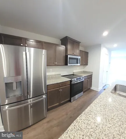 a large kitchen with stainless steel appliances granite countertop a refrigerator and a sink