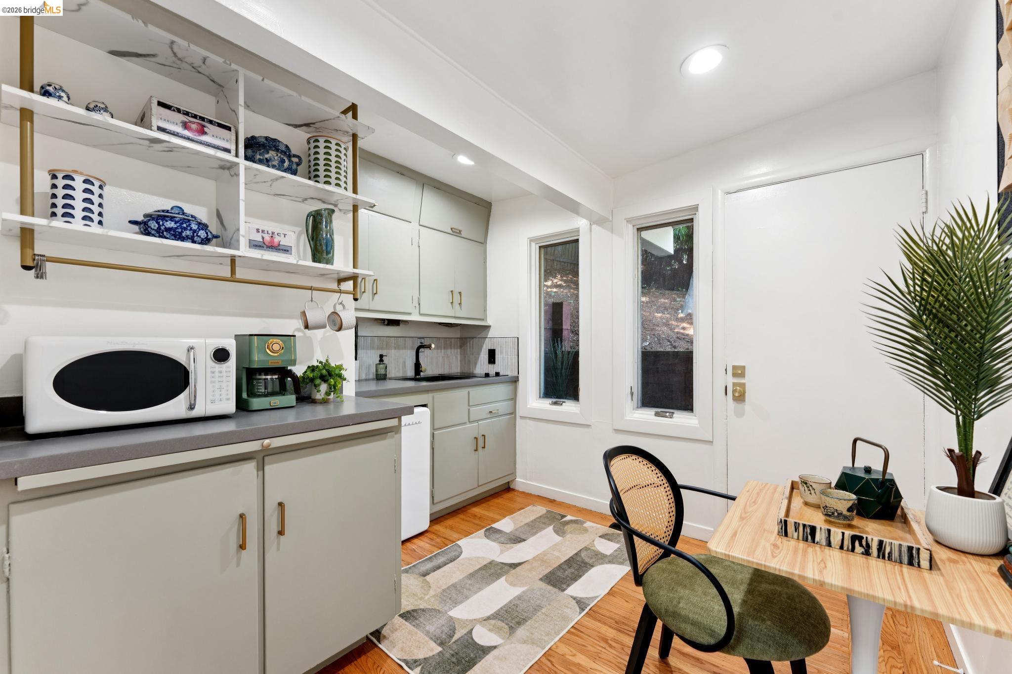 2301 Oak Street Berkeley, CA 94708 - Photo 28 of 61 Compact kitchen area featuring wood-finish flooring, light cabinetry, and a contemporary open shelving unit with a stone-look finish
