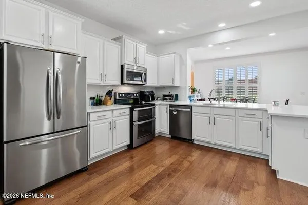 a kitchen with white cabinets stainless steel appliances and wooden floors