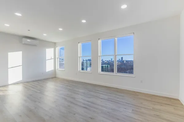a view of an empty room with a window and wooden floor