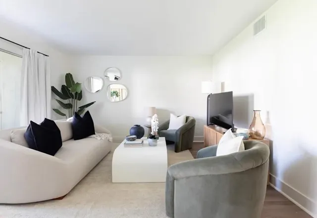 a living room with couches a coffee table and a flat screen tv with wooden floor