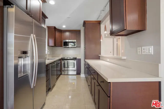 a kitchen with stainless steel appliances granite countertop a refrigerator a stove and a sink with wooden floor