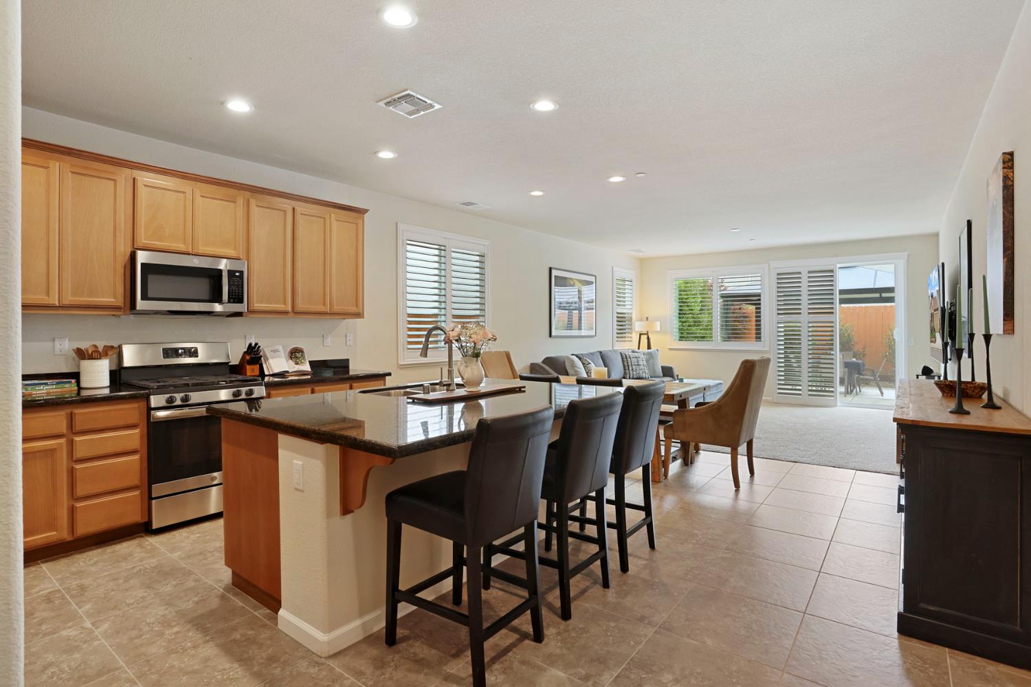 3828 Lookout Drive Modesto, CA 95355 - Photo 7 of 39 a kitchen with stainless steel appliances granite countertop wooden cabinets a stove a sink a dining table and chairs