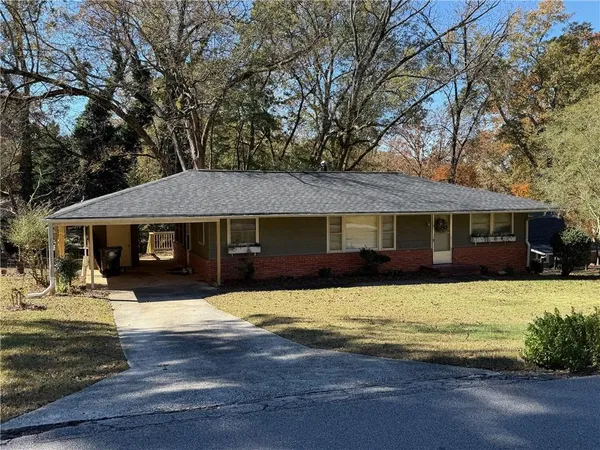 a front view of a house with a yard covered with trees