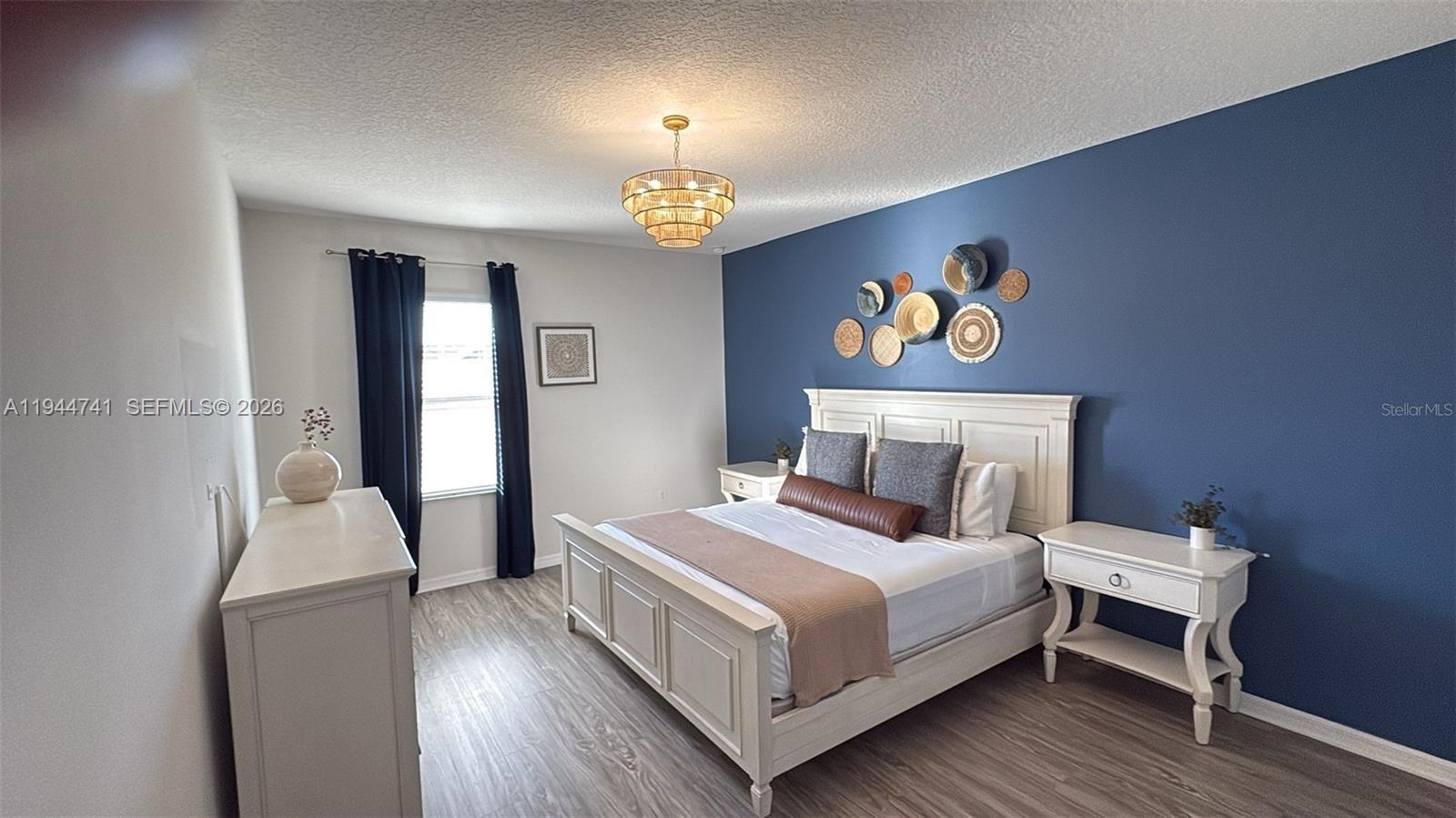 4445 Shiva Loop, Unit 4445 Kissimmee, FL 34746 - Photo 13 of 31 a bedroom with a bed and a chandelier