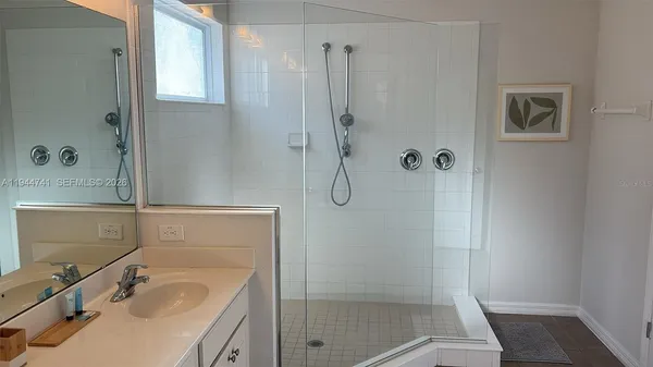 a bathroom with a sink a glass door shower and a mirror