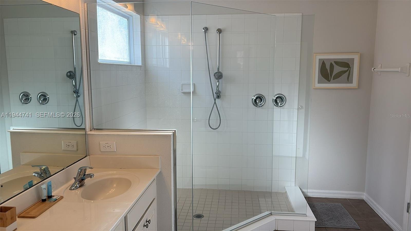 4445 Shiva Loop, Unit 4445 Kissimmee, FL 34746 - Photo 24 of 31 a bathroom with a sink a glass door shower and a mirror