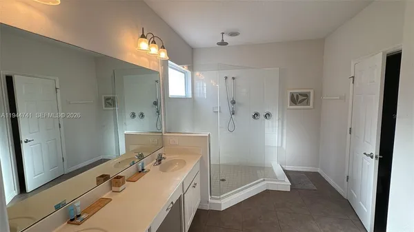 a bathroom with a double vanity sink a large mirror and shower