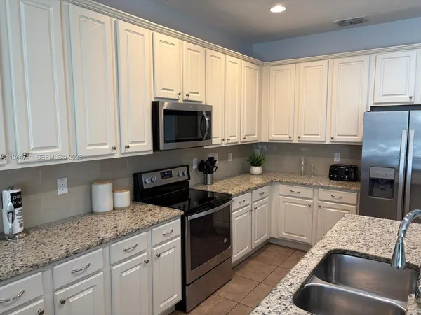 a kitchen with stainless steel appliances granite countertop a sink a stove a microwave and cabinets