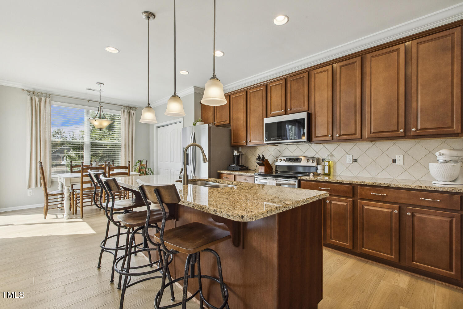 3604 Norman Blalock Road Willow Spring, NC 27592 - Photo 21 of 51 a kitchen with stainless steel appliances granite countertop a stove a sink a microwave a dining table and chairs with wooden floor