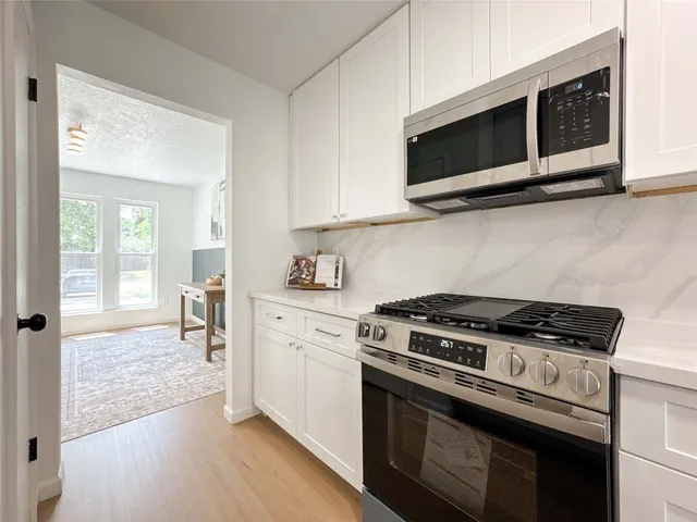 a kitchen with stainless steel appliances a stove a microwave and white cabinets