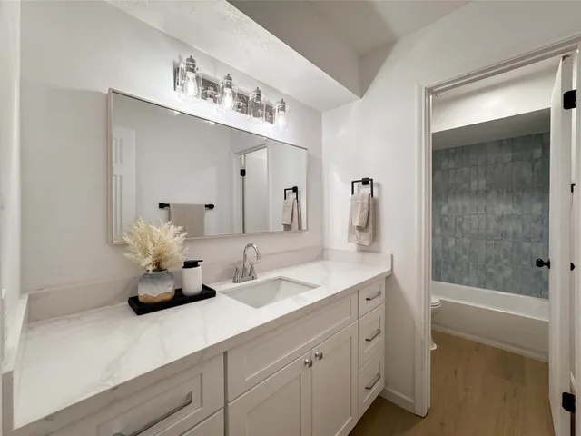 a bathroom with a double vanity sink mirror and bathtub