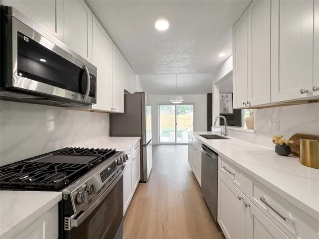 a kitchen with stainless steel appliances a sink a stove and microwave