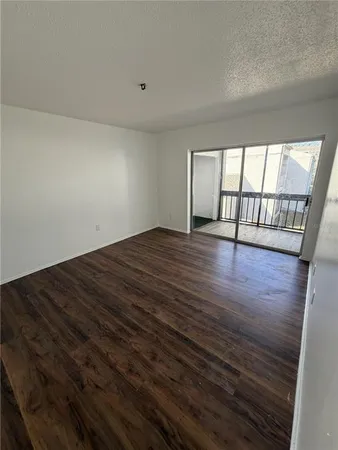 a view of an empty room with wooden floor and door