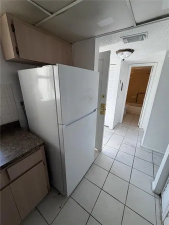 a view of a refrigerator in kitchen and an empty room