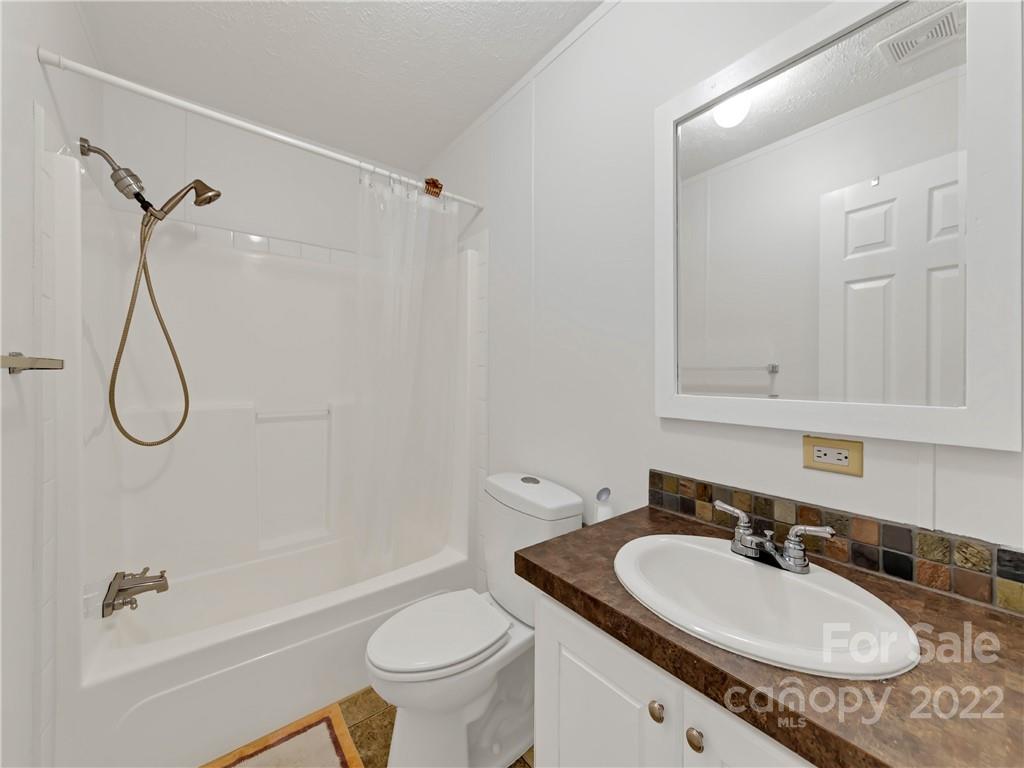 70 Sugar Cove Road Clyde, NC 28721 - Photo 13 of 21 a bathroom with a granite countertop sink a toilet and a bathtub