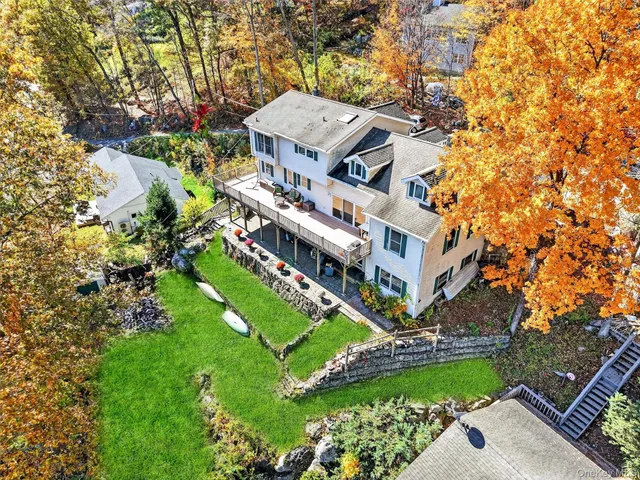 a view of a brick house with a yard large tree and plants