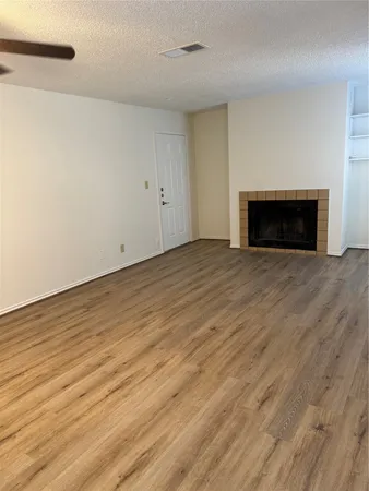 a view of empty room with wooden floor and fireplace