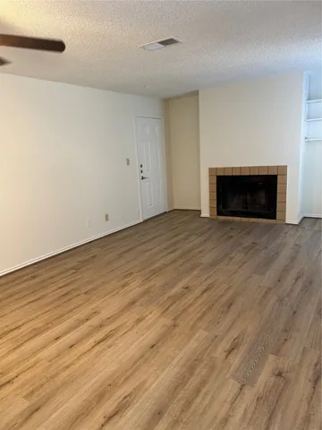 a view of empty room with wooden floor and fireplace