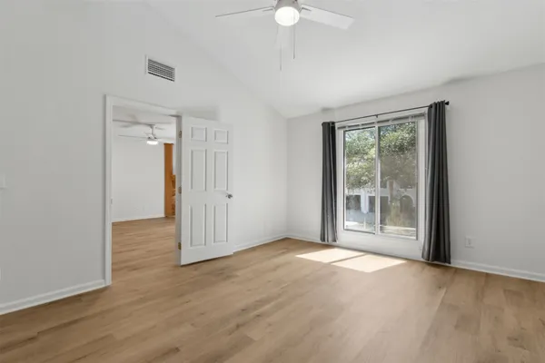 a view of an empty room with wooden floor and a window