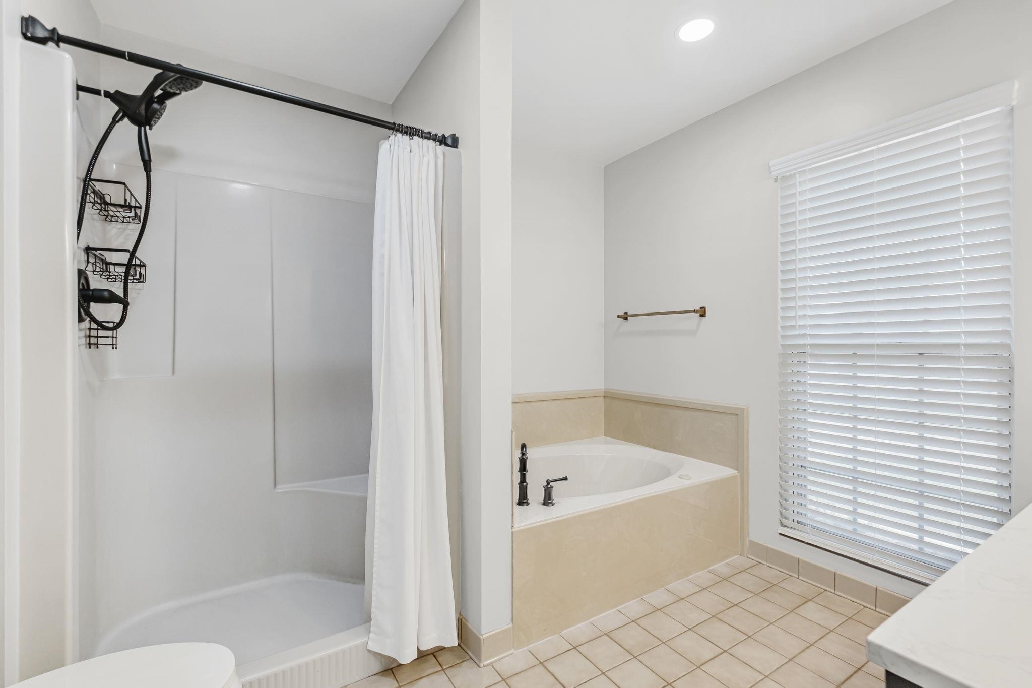 4729 Cedar Ridge Drive Millington, TN 38053 - Photo 20 of 40 Bathroom featuring a built-in tub with dark-finish fixtures, a separate shower with a curved shower rod, and tile flooring
