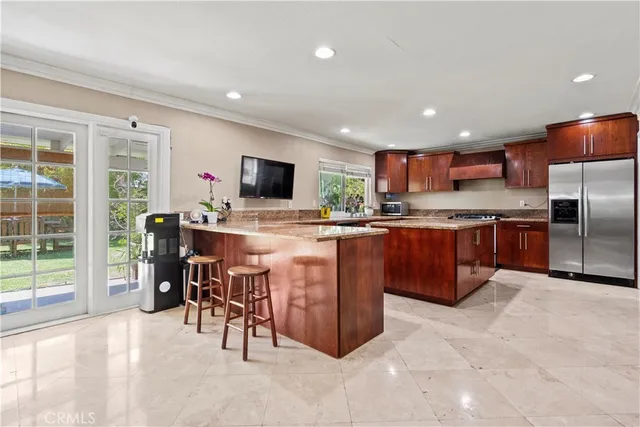 a kitchen with stainless steel appliances kitchen island granite countertop a stove refrigerator and a sink with cabinets