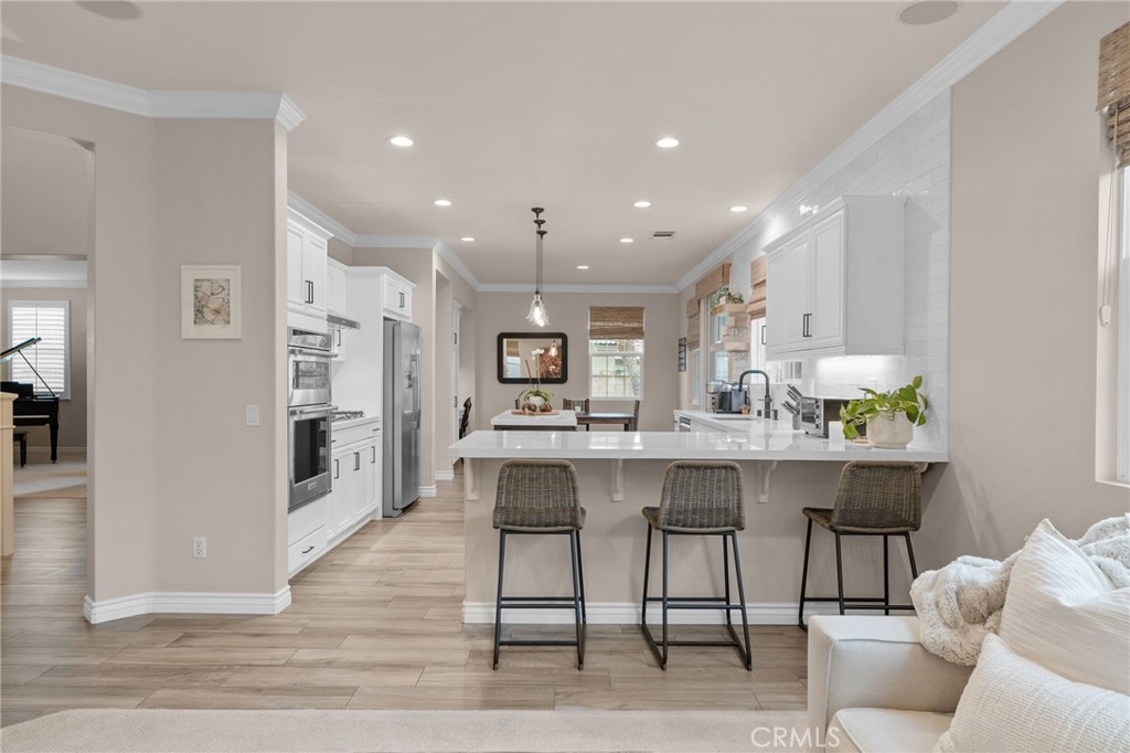 5156 Tahoe Place Rancho Cucamonga, CA 91739 - Photo 18 of 49 a kitchen with stainless steel appliances a dining table chairs and wooden floor