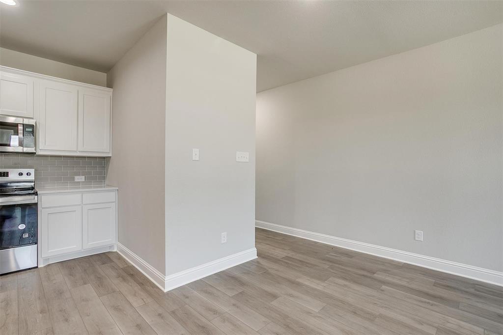 6807 Robert Reed Drive Arlington, TX 76001 - Photo 10 of 37 a view of a kitchen with white cabinets and wooden floor