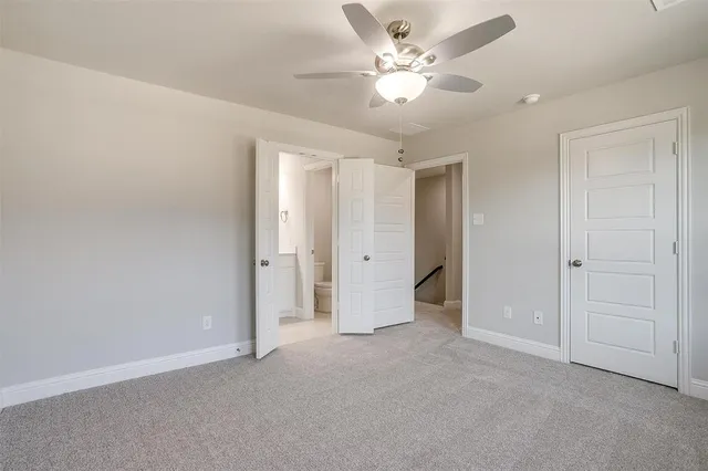 an empty room with a ceiling fan and a bathroom