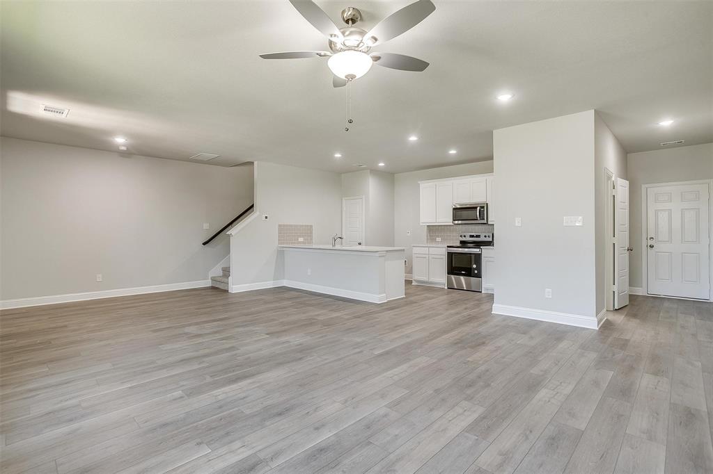 6807 Robert Reed Drive Arlington, TX 76001 - Photo 7 of 37 a view of an empty room with wooden floor and a ceiling fan