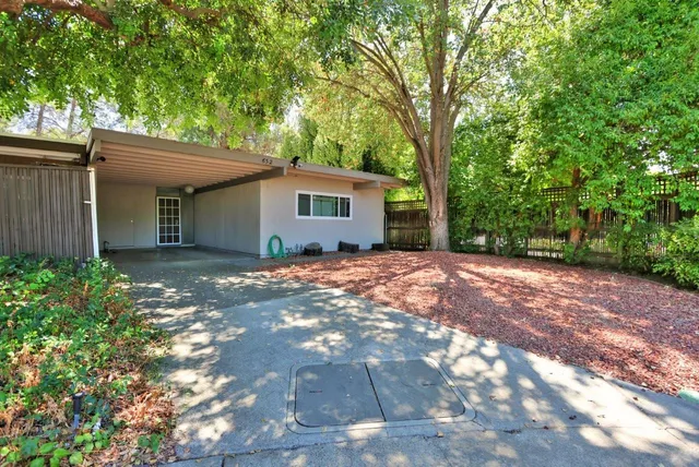 a backyard of a house with large trees and brick walls