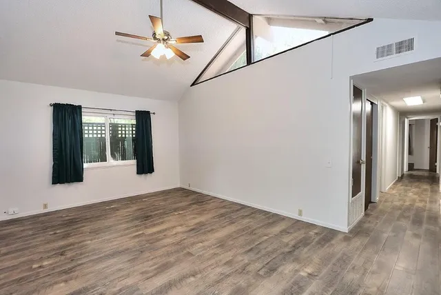 a view of an empty room with a window and wooden floor