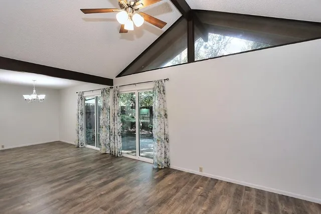 an empty room with wooden floor fan and windows