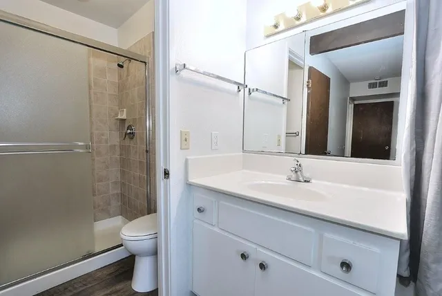 a bathroom with a granite countertop sink toilet and shower