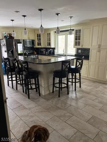 a kitchen with stainless steel appliances kitchen island granite countertop a table chairs and a refrigerator