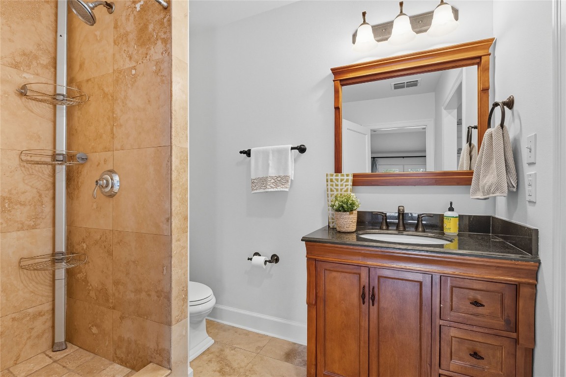 3003 Burleson Road Austin, TX 78741 - Photo 24 of 35 a bathroom with a granite countertop sink toilet a mirror and shower