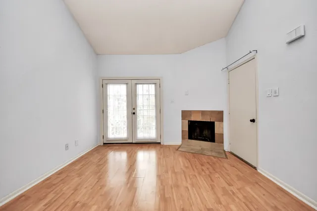 an empty room with wooden floor fireplace and windows