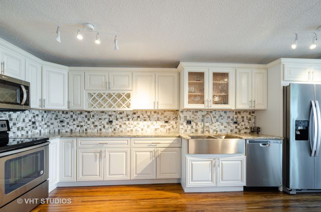 a kitchen with stainless steel appliances kitchen island granite countertop a refrigerator and a stove top oven