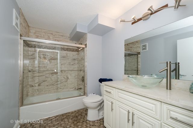 a bathroom with a granite countertop sink a toilet a mirror and shower