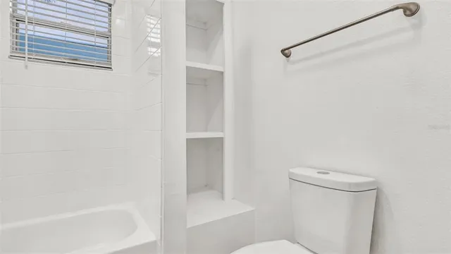 a white toilet sitting next to a bath tub