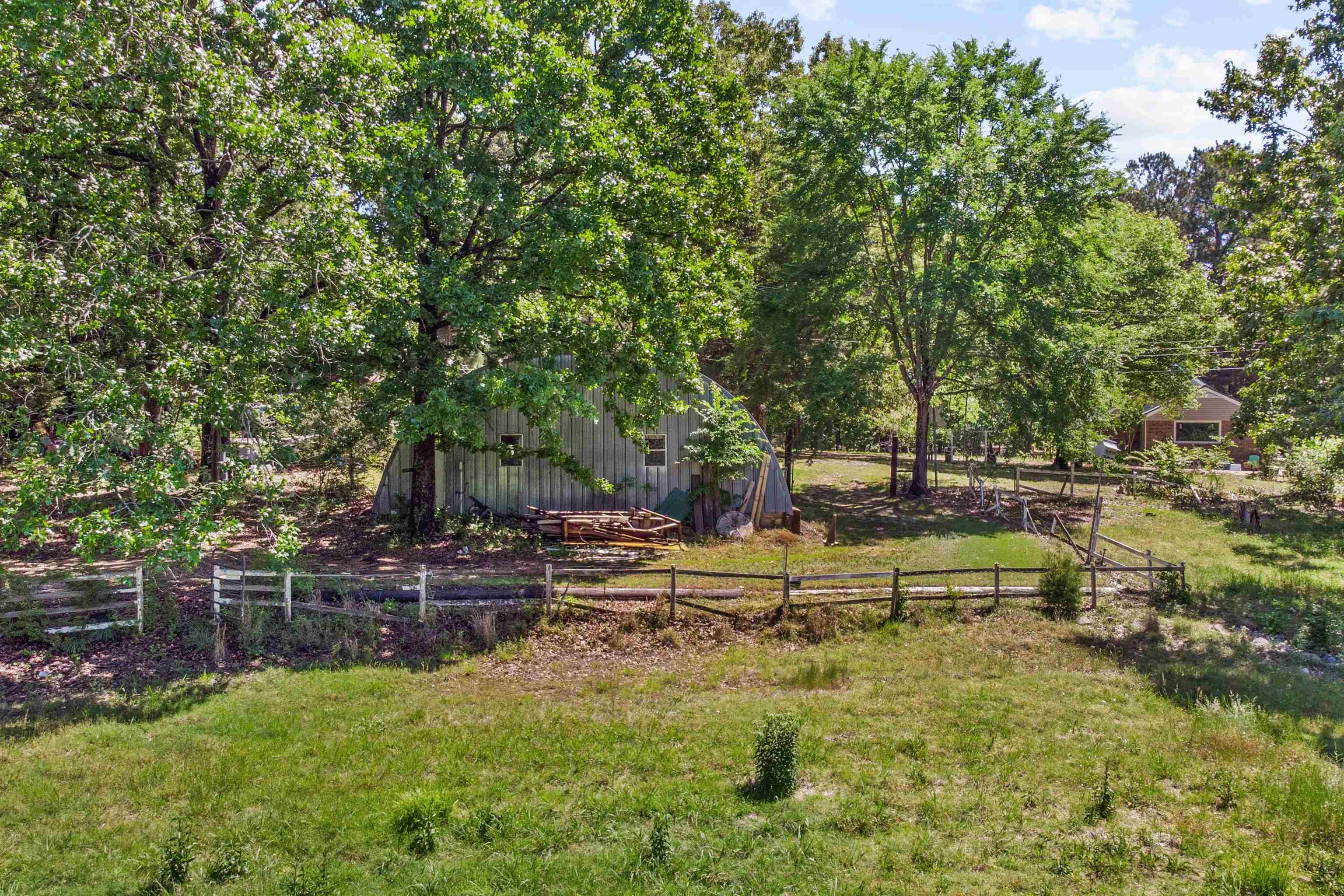 1147 North Collierville Arlington Road Collierville, TN 38017 - Photo 16 of 17 Expansive outdoor area featuring mature trees, a metal-sided outbuilding, and natural wood fencing